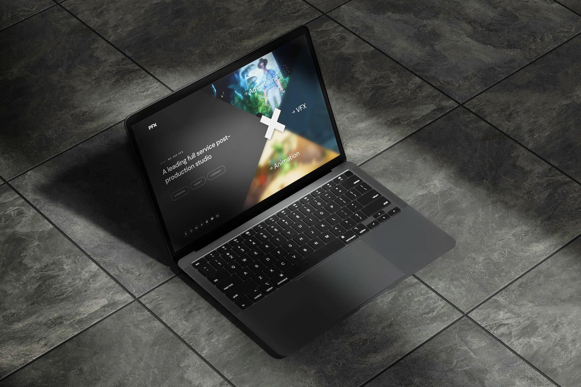 Notebook na tmavé dlažbě s úvodní stránkou PFX: „A leading full service post-production studio“ vedle tří nakloněných panelů pro reklamu, VFX a animaci.