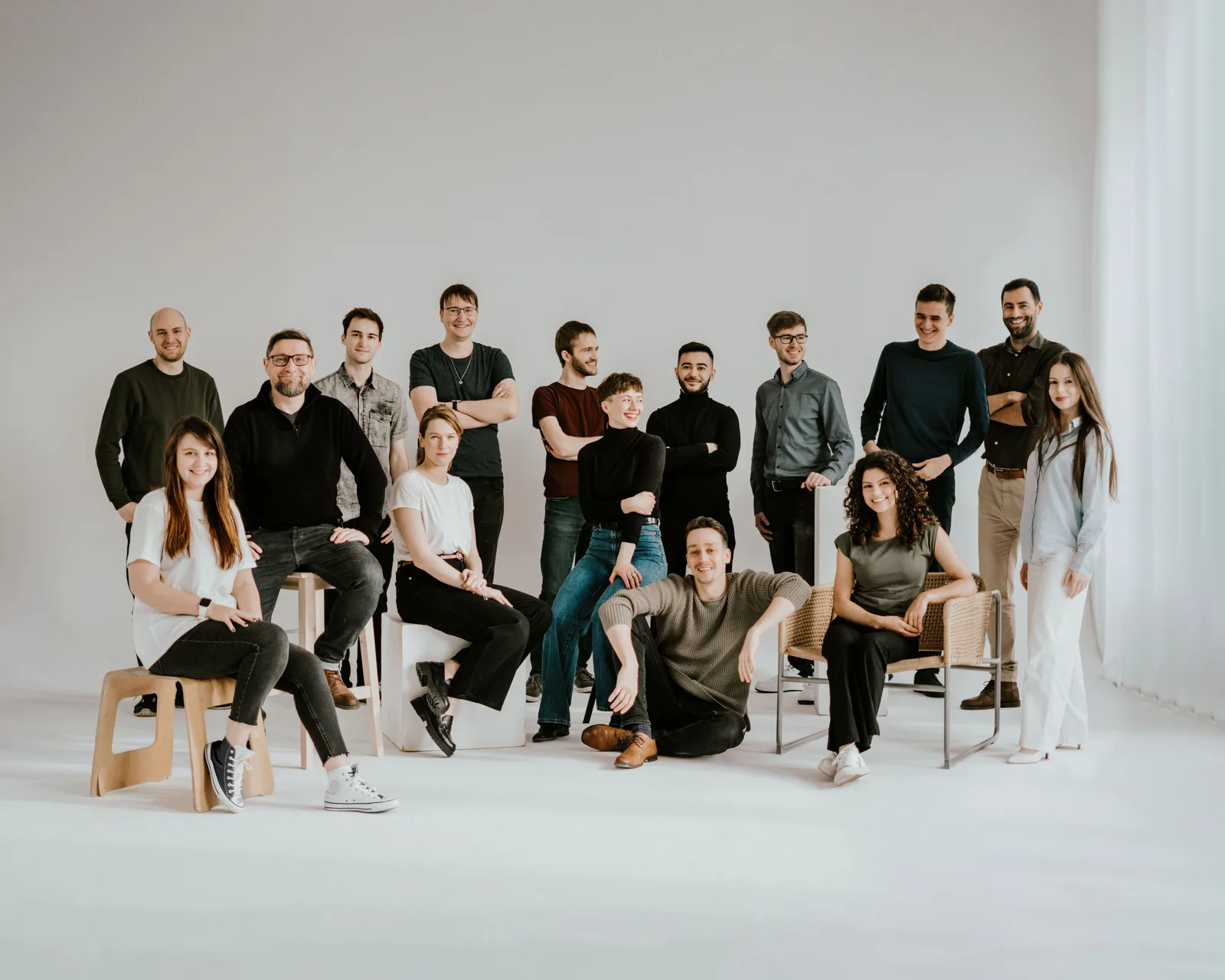 The Qubix team gathered together in a bright studio, some seated and some standing, smiling.